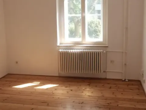 Leere Eigentumswohnung mit Holzboden und großem Fenster