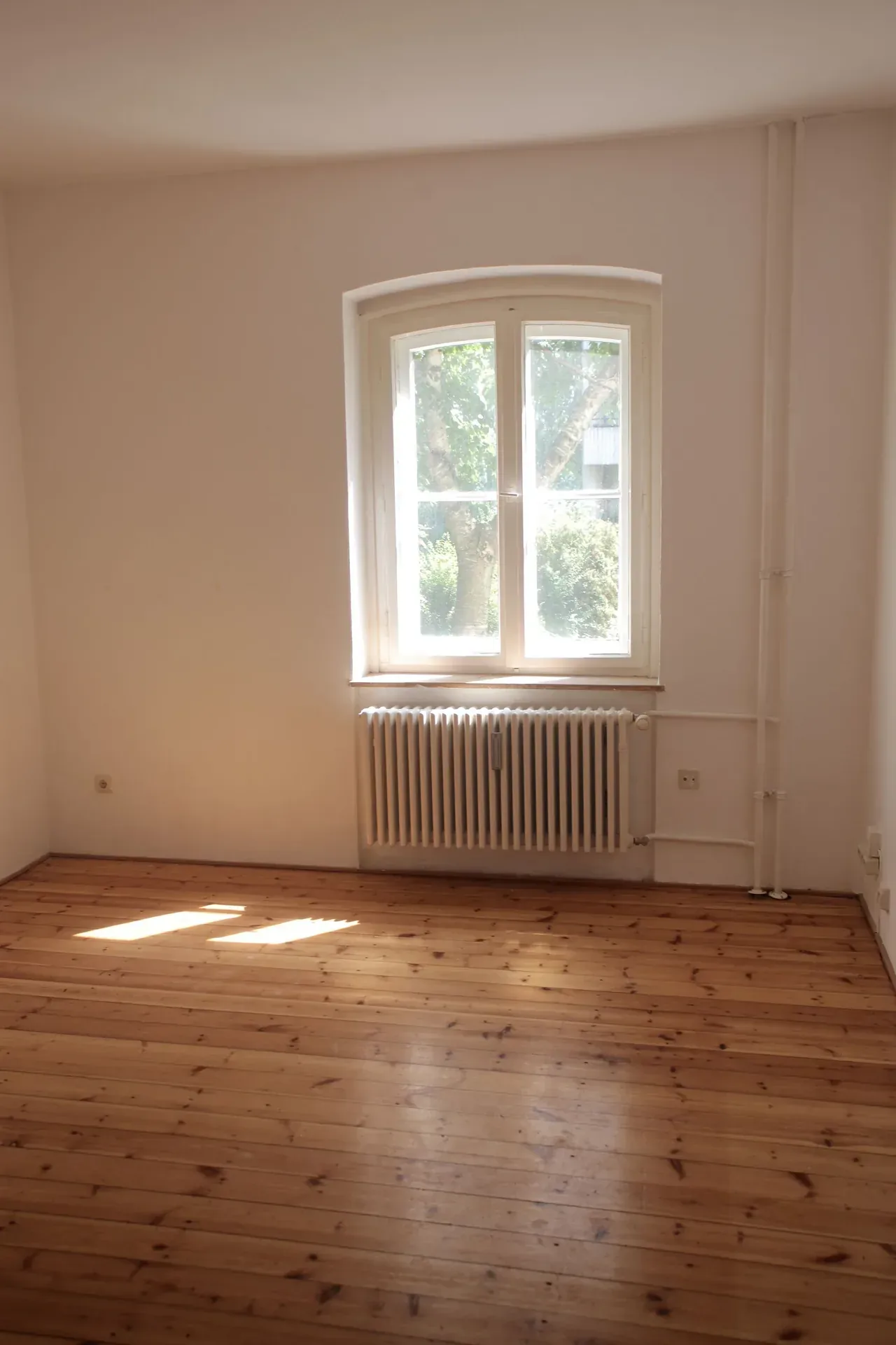 Leere Eigentumswohnung mit Holzboden und großem Fenster